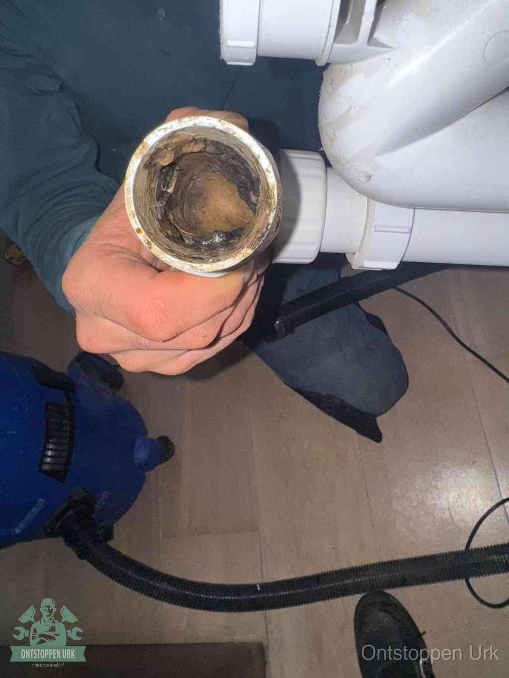 Een losgekoppeld PVC-afvoerbuisstuk dat van binnen volledig is dichtgeslibd met vet en vuil, de meest voorkomende oorzaak van verstoppingen in Urk