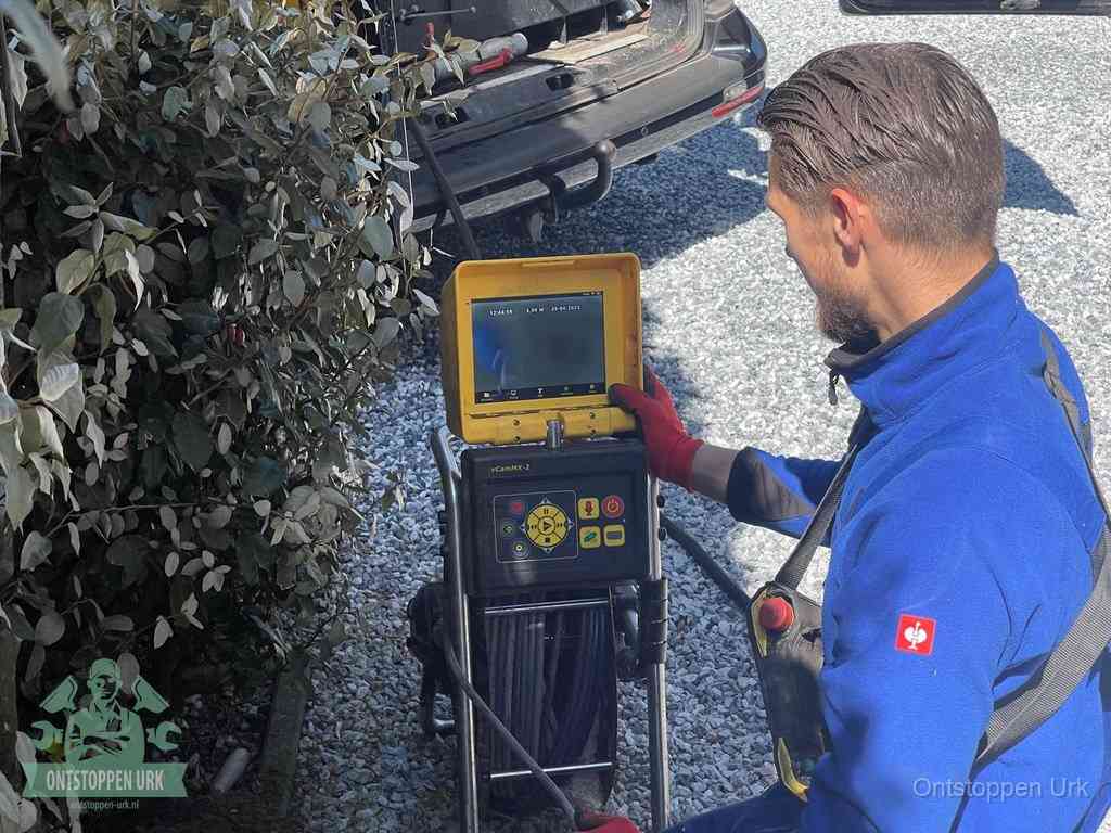 Een monteur bedient een rioolinspectiecamera met monitor en haspel om de verstopping in beeld te brengen in Urk