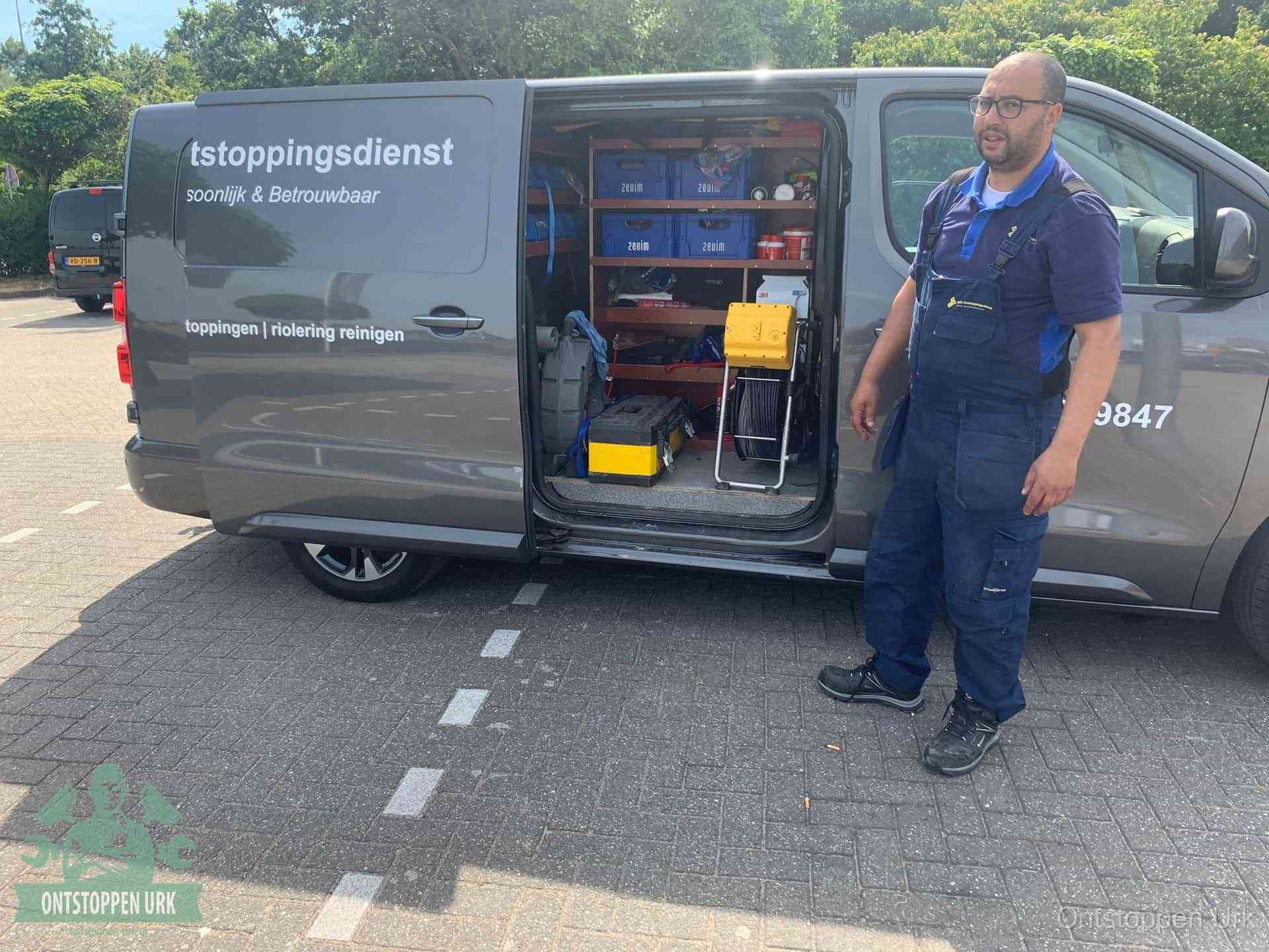 Een monteur staat klaar bij zijn bedrijfsbus met gereedschap, de vaste werkwijze van de ontstoppingsdienst in Urk